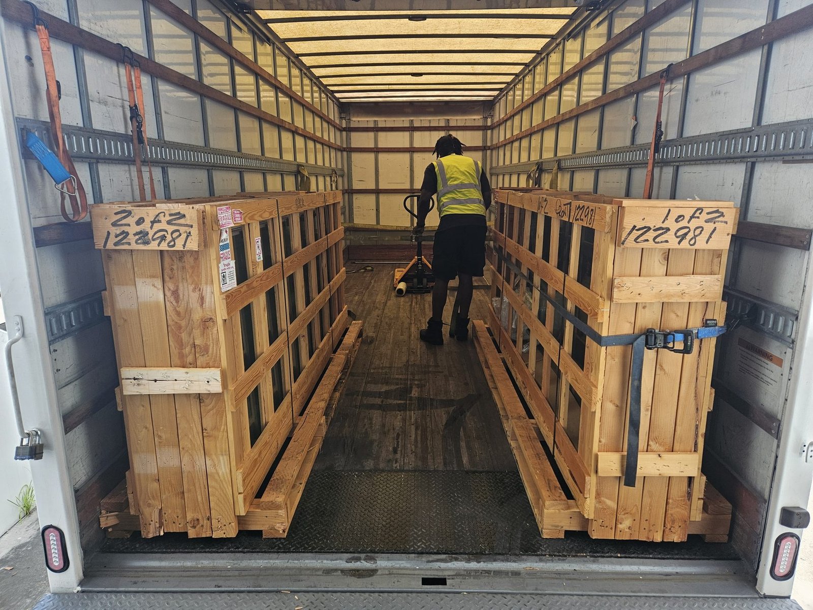 Crated freight being moved with a pallet jack inside a trailer