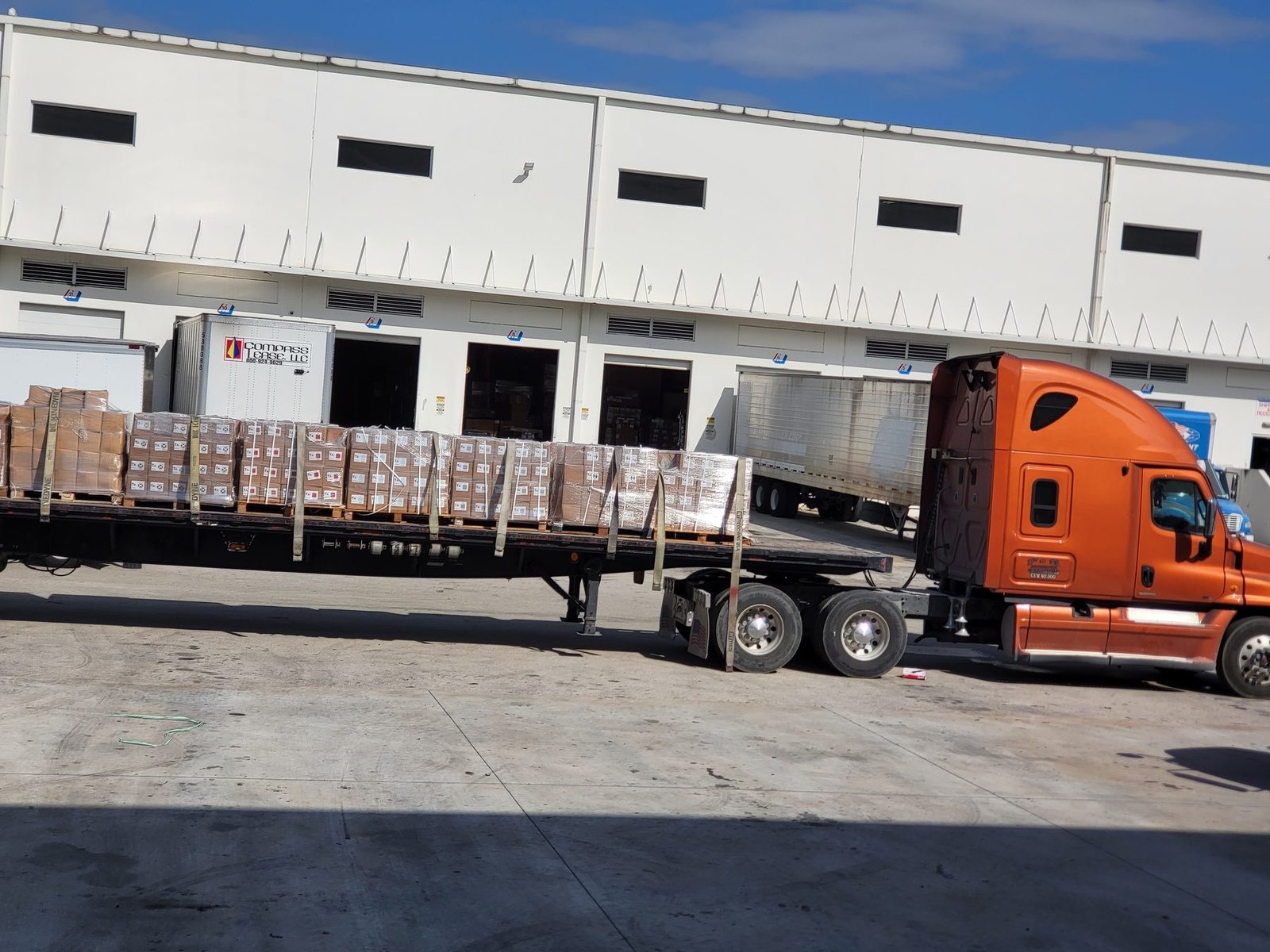 Flatbed loaded with wrapped pallets at the dock