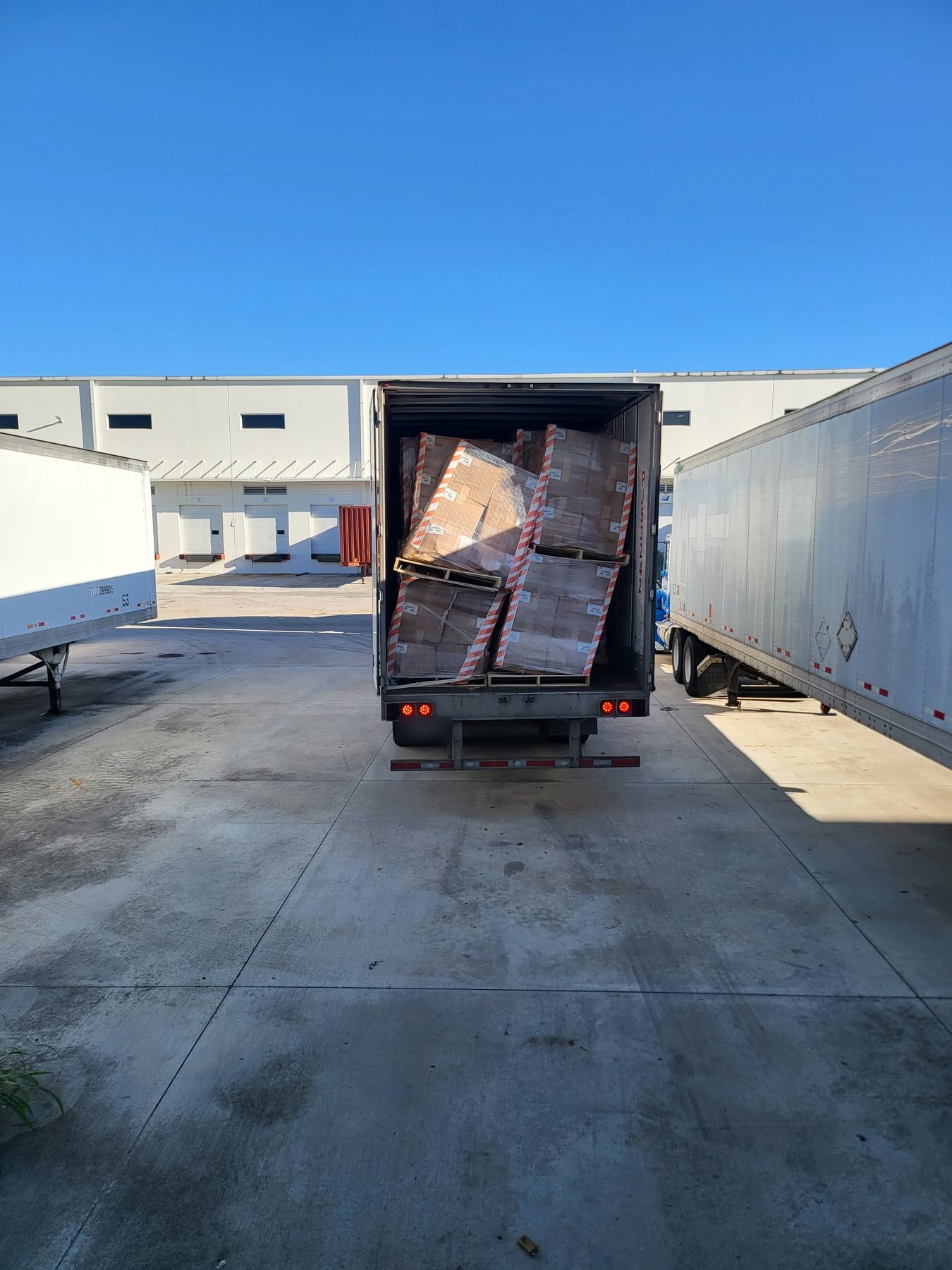 A load that has shifted and collapsed inside a trailer, with leaning pallets and tipped cartons